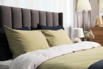 Comfortable bed with cushions and bedding in room. Stylish interior