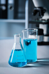Different laboratory glassware with light blue liquid on table