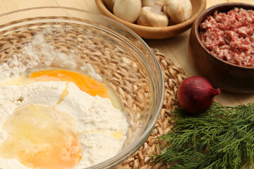 Bowl with flour, eggs and products on table, closeup