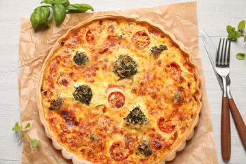 Delicious homemade vegetable quiche and cutlery on wooden table, flat lay