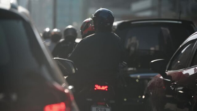 Many motorcycles and cars wait for the green traffic light in the city with a lot of  pollution.