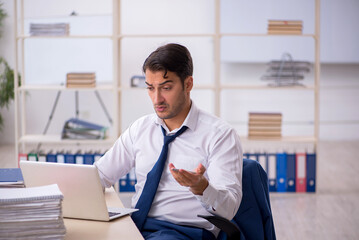 Young male employee and too much work in the office