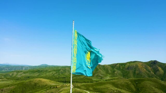 Aerial shot of flag of Kazakhstan waving on flagpole. Flag of Kazakhstan waving in the wind. Drone footage of the Kazakh flag. Symbol of Kazakhstan.