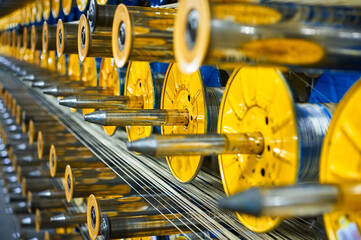Fototapeta na wymiar Yellow bobbins and metal spools in production workshop