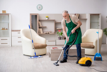 Old male contractor cleaning the house