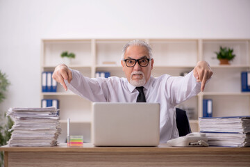 Obraz premium Old male employee working in the office