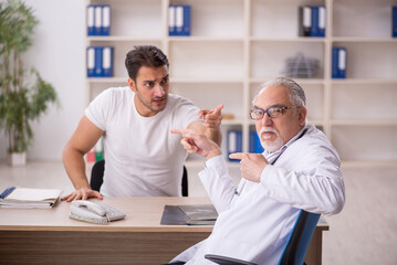 Obraz premium Young male patient visiting old male doctor