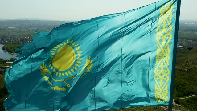 Close up of Kazakh flag flying on wind. Waving flag on flagpole against blue sky in Kazakhstan. Highly detailed flagpole of Republic Kazakhstan on bright sunny day