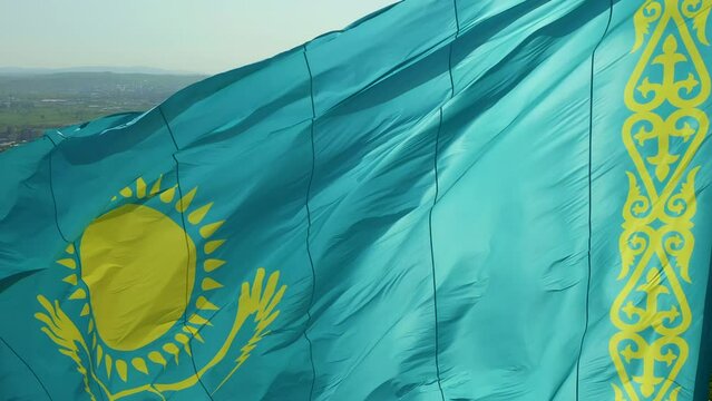 Close up of Kazakh flag flying on wind. Waving flag on flagpole against blue sky in Kazakhstan. Highly detailed flagpole of Republic Kazakhstan on bright sunny day