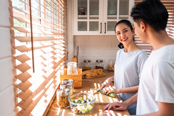 Fototapeta na wymiar Asian young new marriage couple spend time together in kitchen at home. 