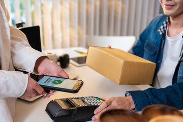 Close up hands of customer using mobile phone paying for goods package. 