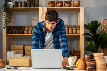Caucasian businessman checking vase goods order for customer on laptop. 