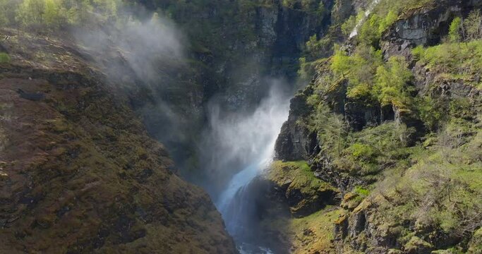 Drone flight in steep misty canyon by western Norway glacial melt waterfall
