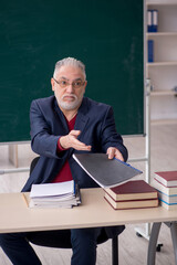 Old male teacher sitting in the classroom