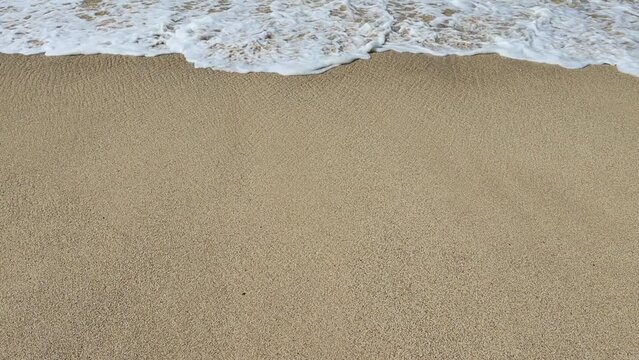 Soothing waves crashing on shore of sandy beach. Show motion video