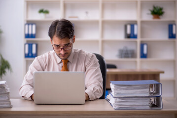 Young male employee and too much work in the office