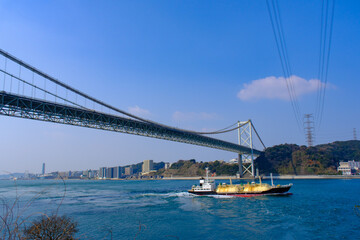 青空の関門橋と関門海峡を走る船
