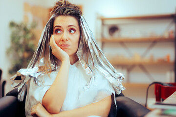 Bored Woman Waiting for her Tin Foiled Hair lights to Develop Color. Frustrated beauty salon customer regretting look change