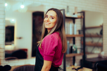 Hairdresser Wearing Uniform Standing in Hair Salon. Cheerful hairstylist working for her own business 
