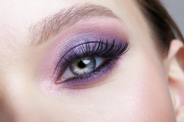 Closeup macro shot of human female eye. Woman with lilac beauty eyes makeup.