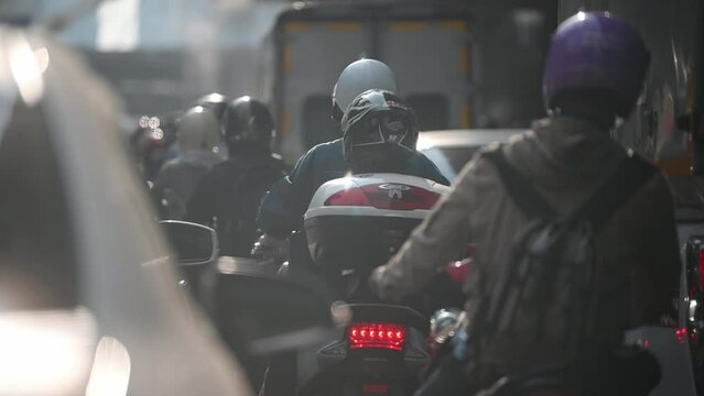Many motorcycles and cars wait for the green traffic light in the city with a lot of  pollution.