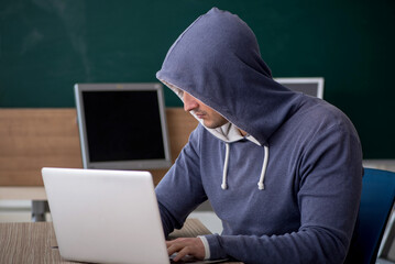 Young male hacker sitting in the classroom