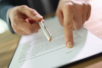 Businessman gives pen and asks to sign contract at table