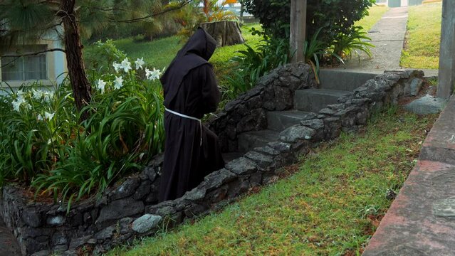 Fraile franciscano monje religioso cat&oacute;lico, cristiano meditando orando rezando caminando por el sendero contemplando la naturaleza en el bosque al amanecer subiendo una cuesta por escaleras