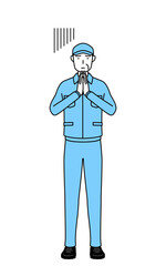 体の前で手を合わせて謝る帽子と作業着姿のシニア男性（経営者、管理職、上司）