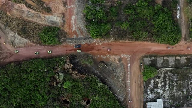 Rising rotating aerial drone wide shot of a group of tourists on four wheelers driving down a dirt road in the tropical coastal village of Sibauma in Tibau do Sul, Rio Grande do Norte, Brazil