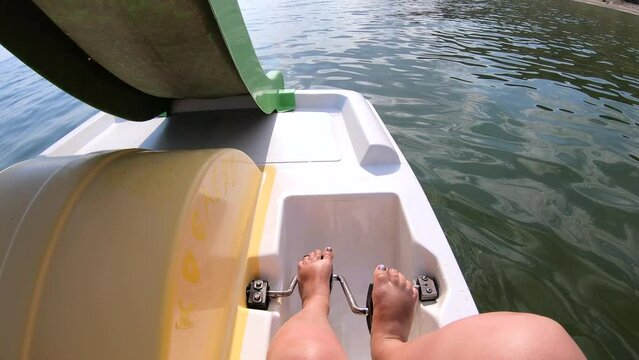 Woman floating on catamaran. Person pedaling with her feet and swimming on catamaran on sea surface with waves on sunny summer day. Active lifestyle recreation leisure sport POV