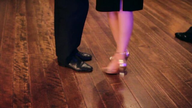 Argentine tango dancers dancing at a Tango party on a wooden parquet floor in an intimate and sensual atmosphere.