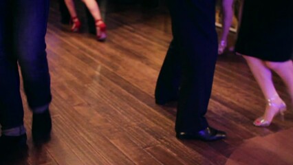 Argentine tango dancers dancing at a Tango party on a wooden parquet floor in an intimate and sensual atmosphere.