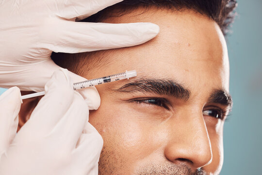 Beauty, botox and eyebrow with a man in studio on a gray background for a plastic surgery injection. Hands, skincare and syringe with a young male person indoor for an antiaging facial filler closeup