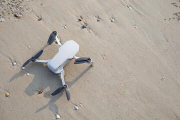 Drone landed on the sand by the sea, top view shot.