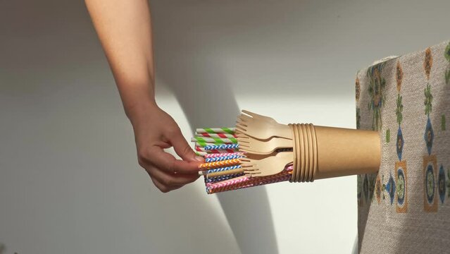 person's hand picks up a paper straw from among other biodegradable products

