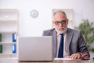Fototapeta premium Old male employee working in the office