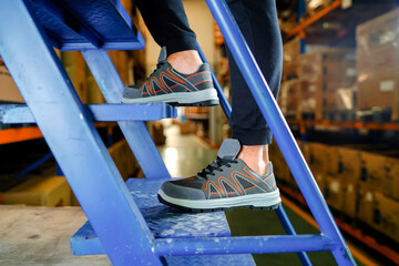 A worker is climbing stairs in a warehouse in a shoe shop