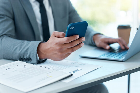 Hands Of Man With Laptop, Phone And Desk At Startup Checking Email, Social Media And Search On Internet At Business. Online Report, Networking And Businessman In Office Typing Or Reading On Cellphone