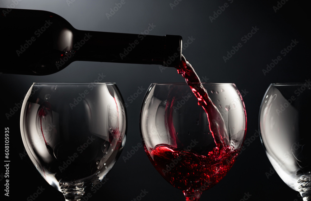 Poster Pouring red wine into a wine glass.