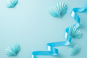 Top view photo of pastel blue origami paper hearts along with a twisted ribbon on an isolated light...