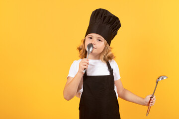 Cooking, culinary and kids. Little boy in chefs hat and apron on studio isolated background.