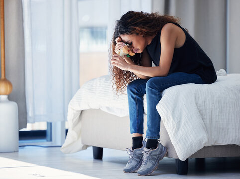 Depression, crying and woman with teddy bear in bedroom for grief, miscarriage or mourning death of kid. Sad mother, tears and person on bed with pain, anxiety or trauma problem, stress or frustrated