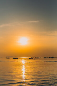 Vertical of silhouette fishing boats at sunset in the sea.