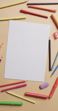 Vertical video of white paper with copy space and pencils on yellow background
