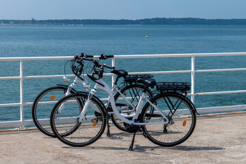 deux vélo électriques sur le bord de mer - obrazy, fototapety, plakaty