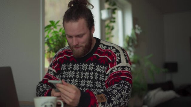 Norwegian Guy With Smartphone And Laptop Is Working On The Table At Home. Close up