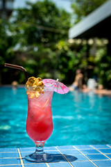 tropical Singapore sling cocktail in tall glass by swimming pool