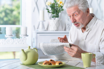 Emotional senior man reading newspaper