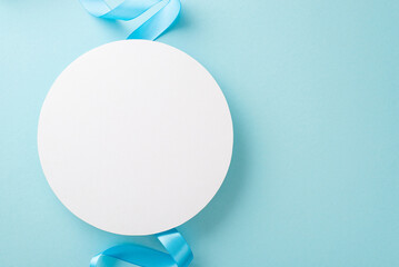 Top view photo of white empty circle with a pastel blue ribbon on an isolated light background with copy-space